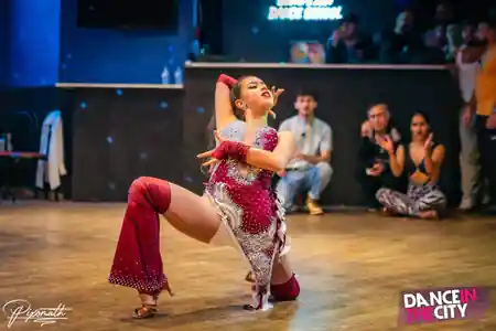 Salsa performer in red costume on the wooden dance floor at Dance In The City venue in Paris