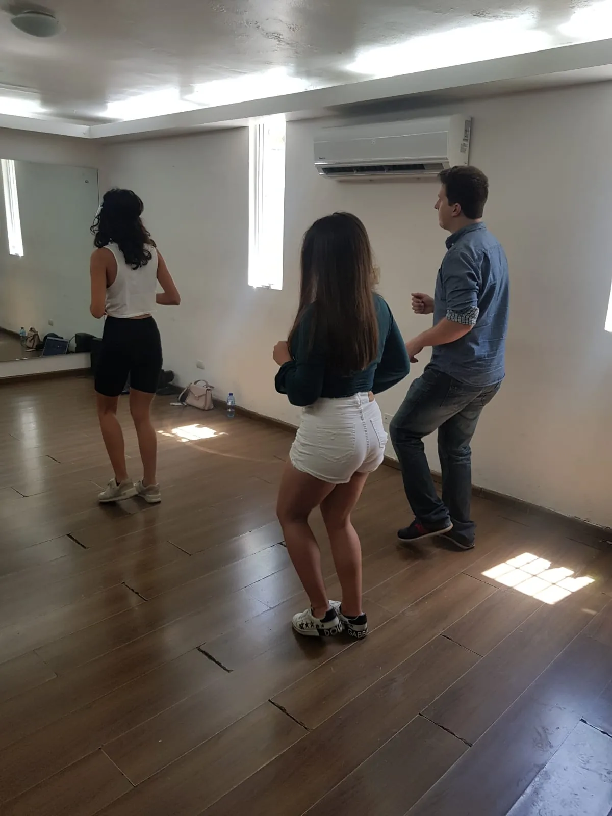 Dancers practicing on the wooden floor with mirror wall at Muévete Studio in Santo Domingo