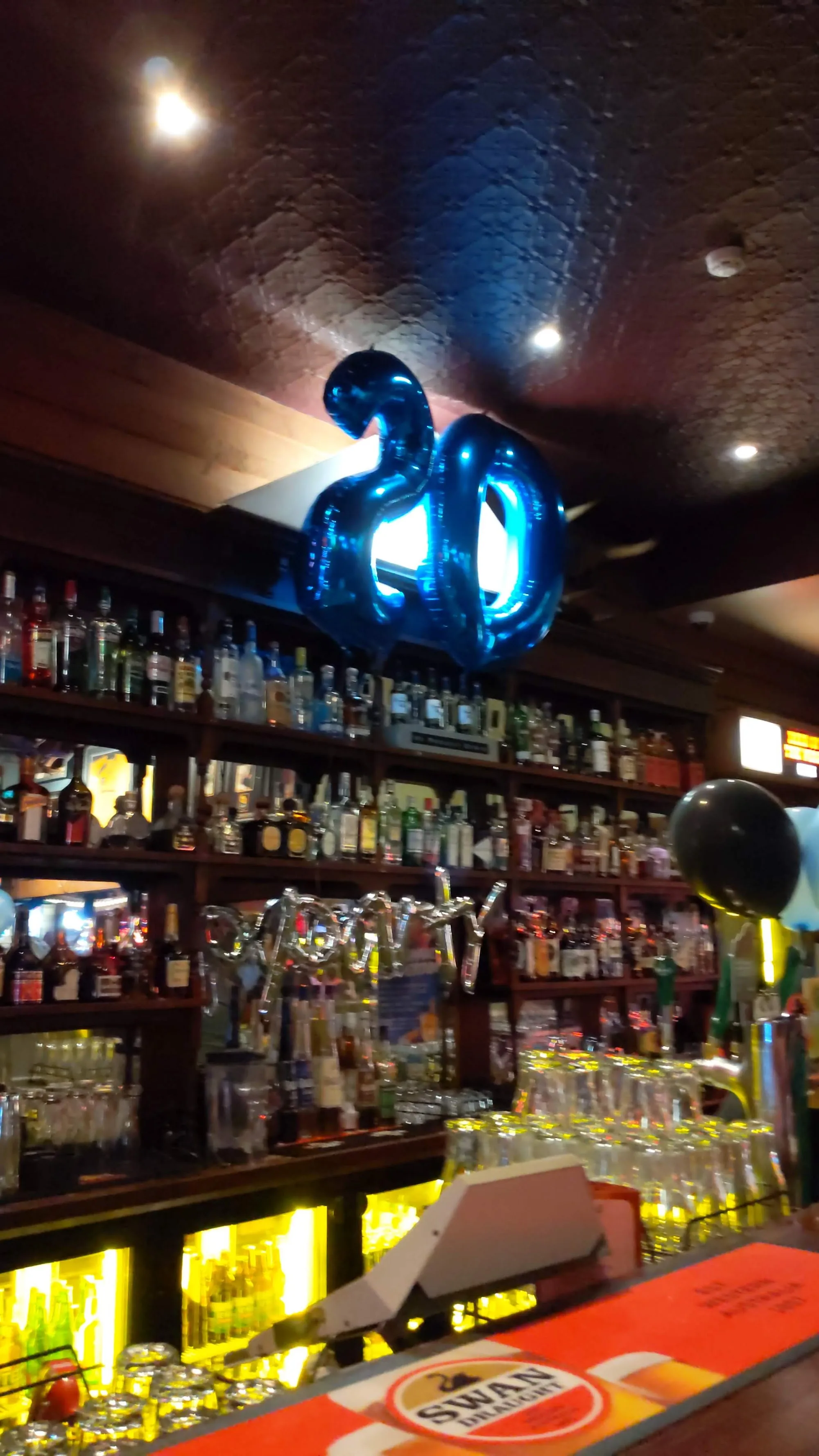 Mustang Bar Perth full bar interior with bottle wall and anniversary balloons
