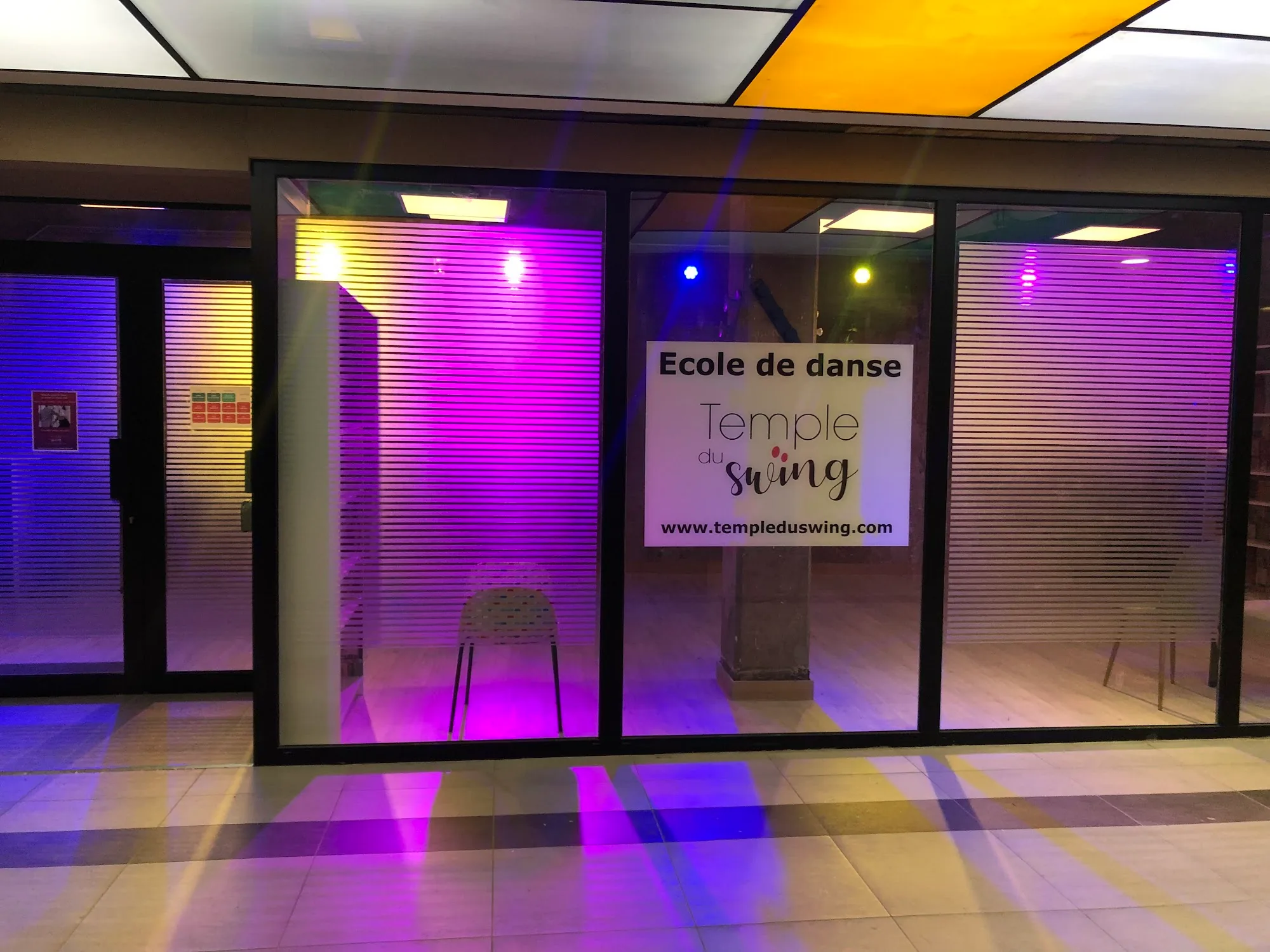 Temple du Swing storefront in Paris lit with purple and yellow ambient lighting at night