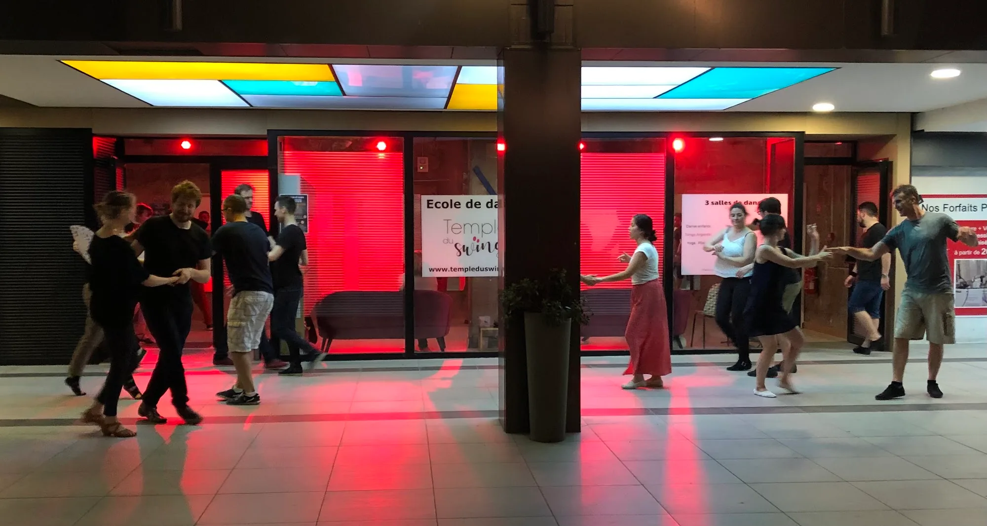 Couples social dancing in the lit corridor of Temple du Swing in Paris