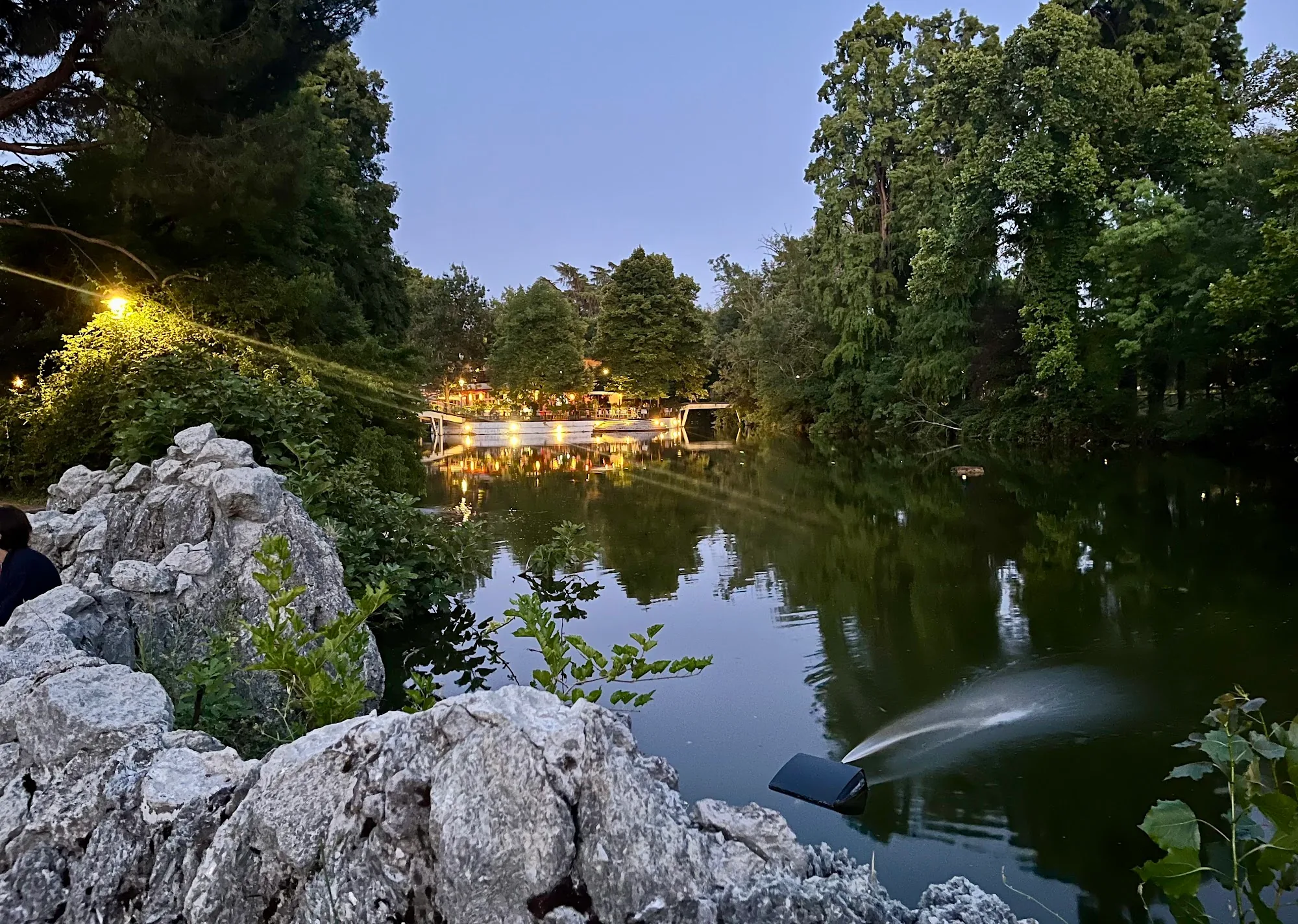 Park lake at dusk with Chalet dei Giardini Margherita lit venue Bologna
