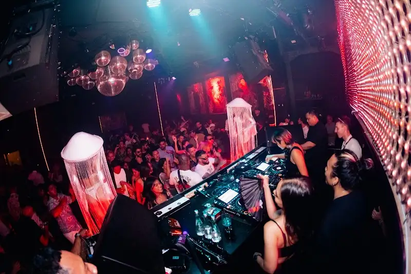 DJ playing to a packed dance floor crowd at Red Ruby nightclub in Bali with disco balls and colored stage lighting — salsa, bachata, kizomba venue in Bali