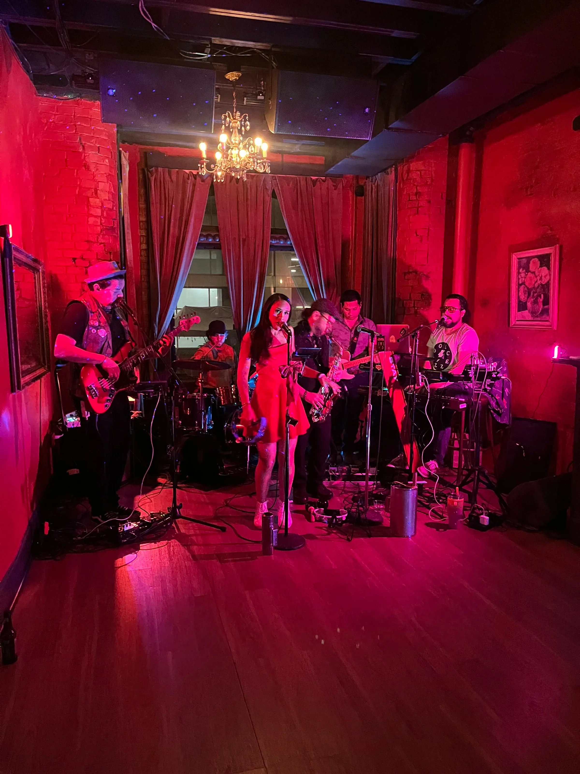 Live band with a singer in a red dress performing under a chandelier in the red-lit, exposed-brick room at Eighteenth Street Lounge, Washington.