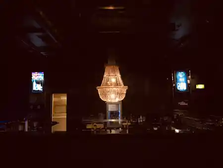 Dark empty bar interior at Le Ciel Bern with a large crystal chandelier and branded screens — salsa, bachata venue in Bern