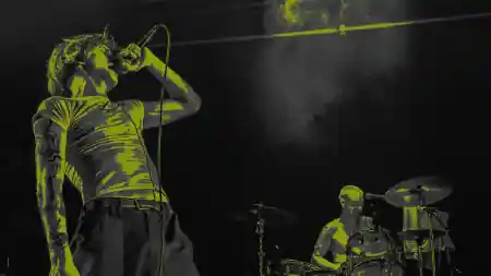 Singer performing live at The Dome with dramatic yellow stage lighting and drummer in the background — salsa venue in London