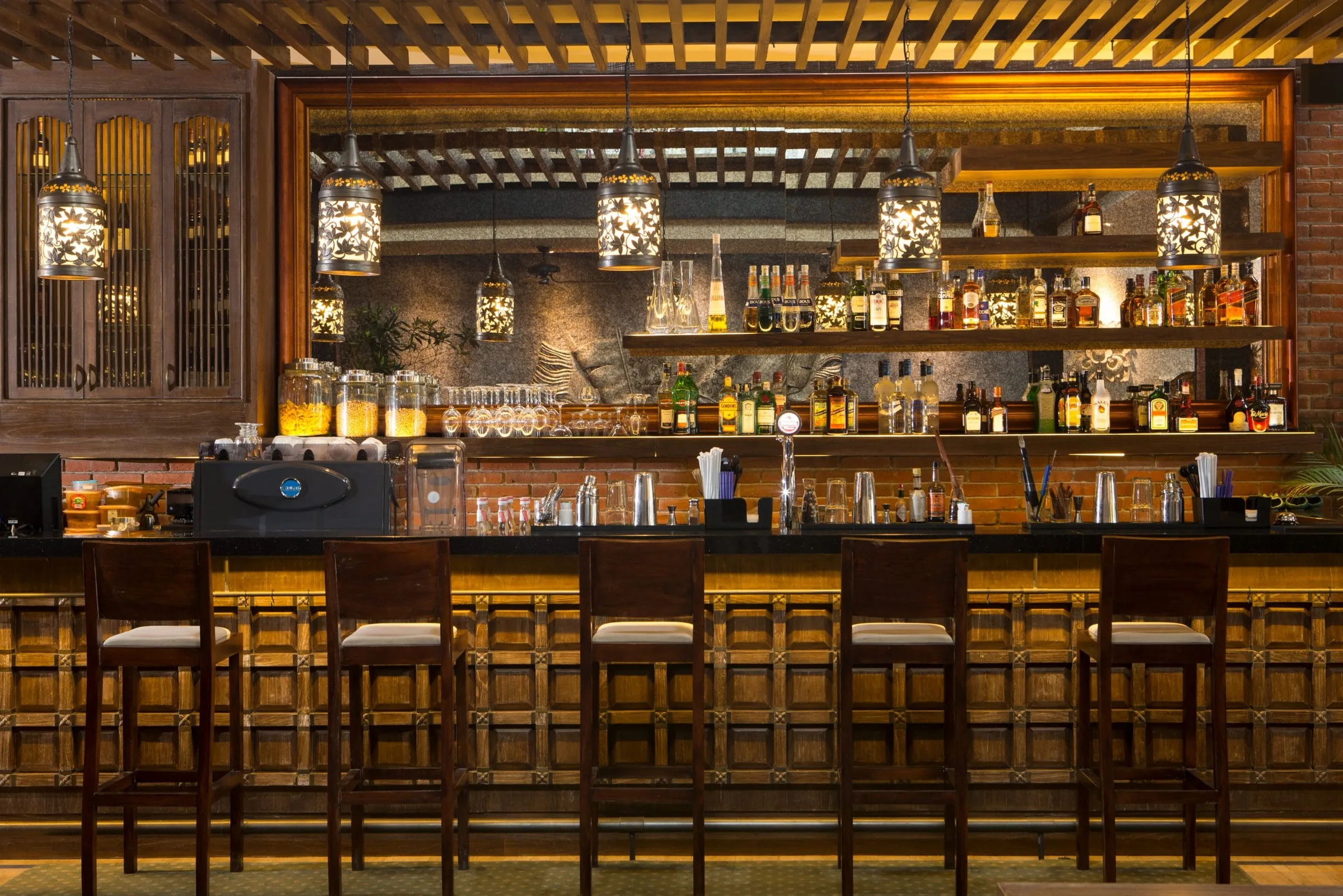 Warmly lit wooden bar with hanging lanterns at Enclave in Bali, Indonesia