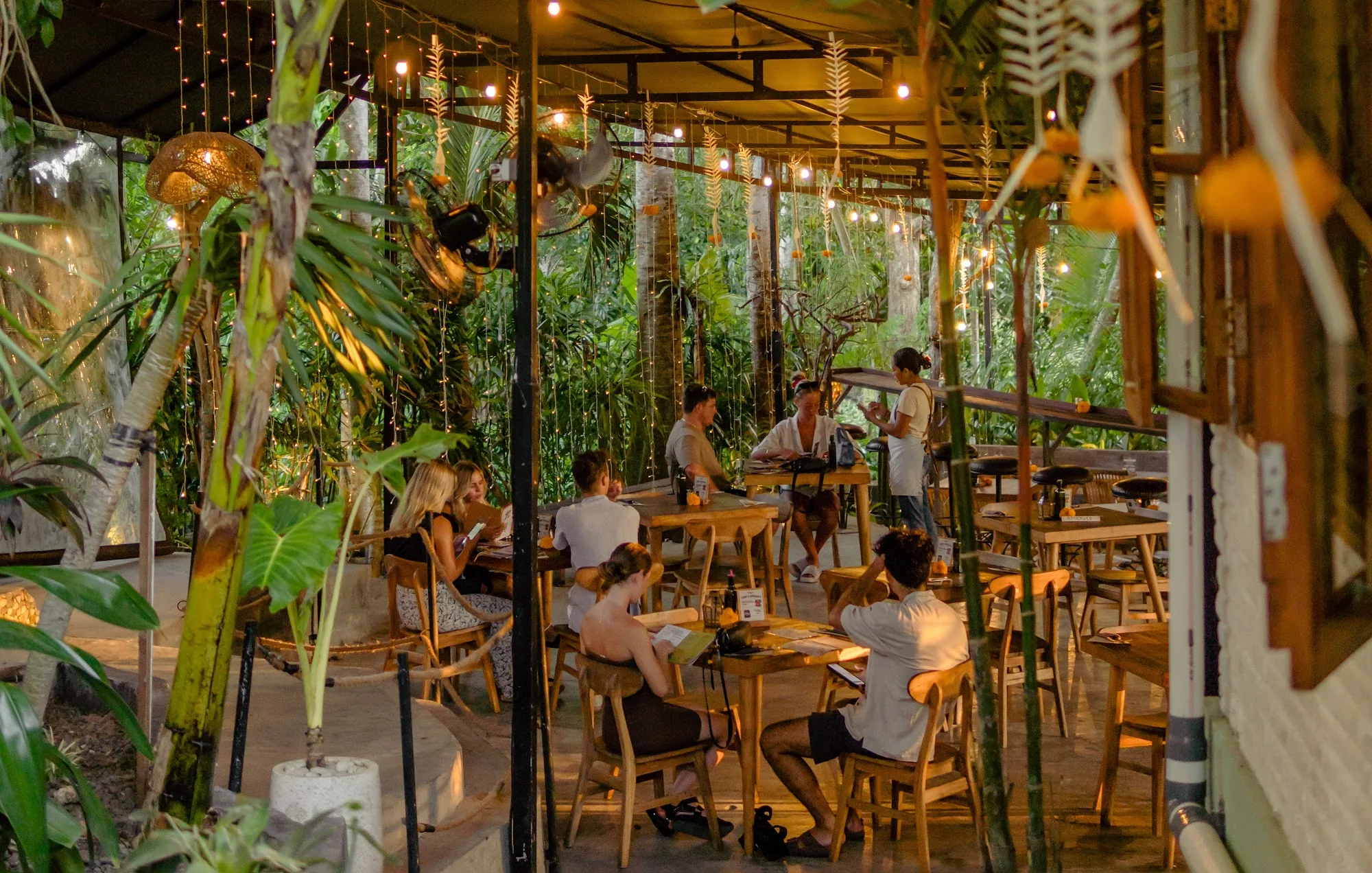 Open-air dining pavilion with fairy lights and tropical plants at Rolling Fork in Bali