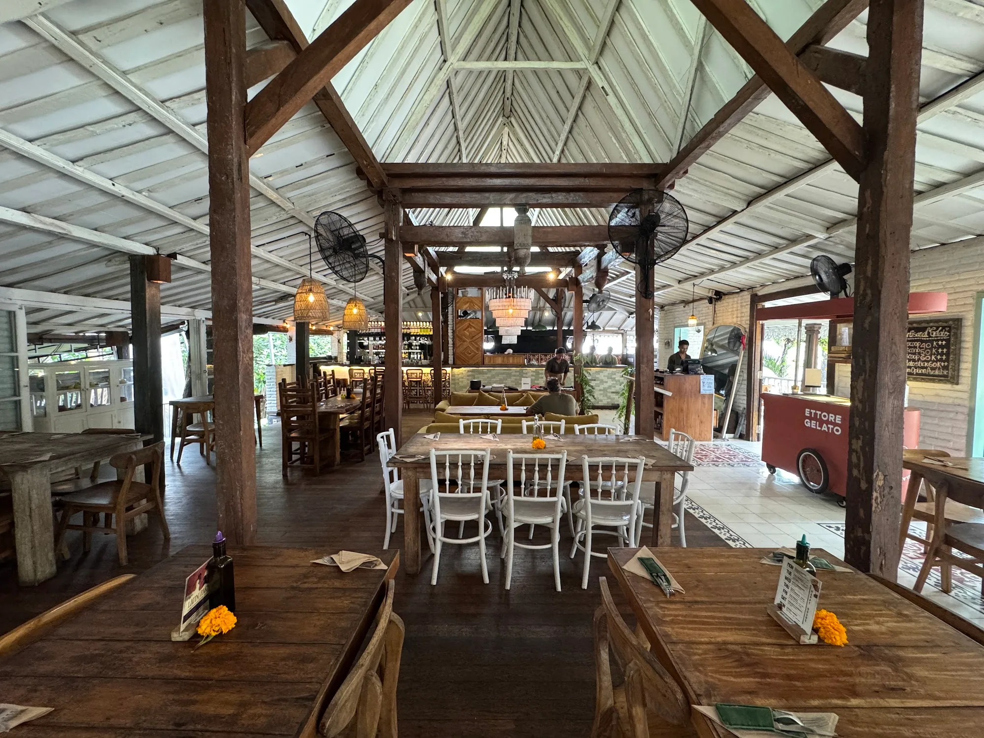 Wide view of the wooden pavilion dining hall and gelato cart at Rolling Fork in Bali