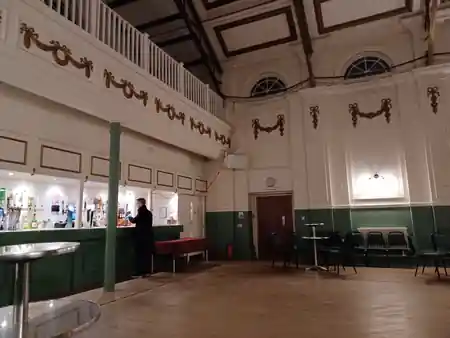 Ornate interior dance hall with wooden floor, balcony and bar at Hammersmith Salsa & Bachata Club in London